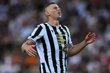 Piłkarz Udinese Calcio w czarno-białej koszulce, z wykrzywioną twarzą, wyraża frustrację. Może to być moment z meczu Serie A, gdzie każda statystyka ma znaczenie.